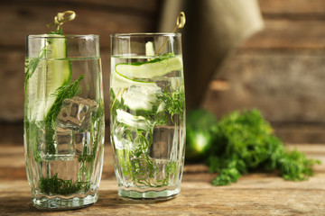 Glasses with fresh organic cucumber water on wooden table