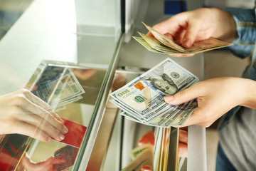 Female hand with money in cash department window. Currency - obrazy, fototapety, plakaty