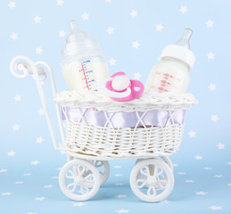 Basket with baby milk bottle and pacifier on blue background