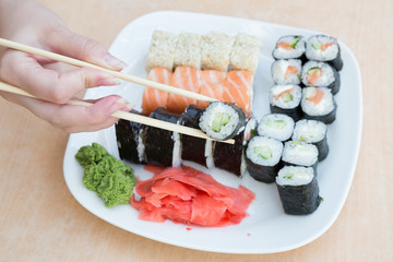 hand holding roll over plate with Japanese food