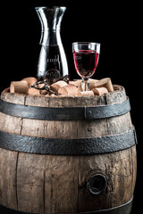 Naklejka premium Red wine glass and carafe on old wooden barrel