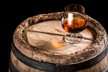 Glass of cognac on old oak barrel