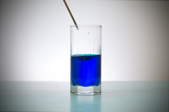 glass of blue liquid and wand