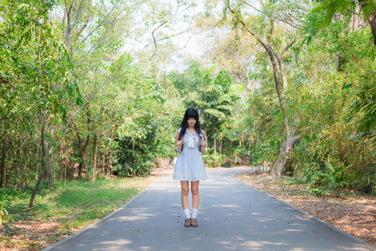 A cute Asian Thai girl is standing on a spring forest path alone