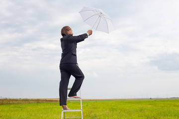 man in black suit with umbrella on stepladder