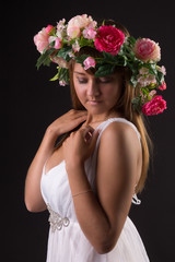 young woman in white dress and wreath of flowers on her head