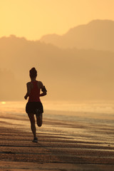 young woman running on sunrise beach