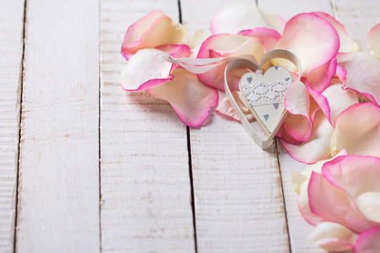 Heart on petals on wooden background