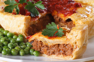 Pieces of meat pie and a garnish of green peas. Horizontal macro