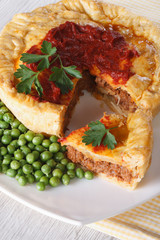 Sliced meat pie and green pea. Vertical close-up