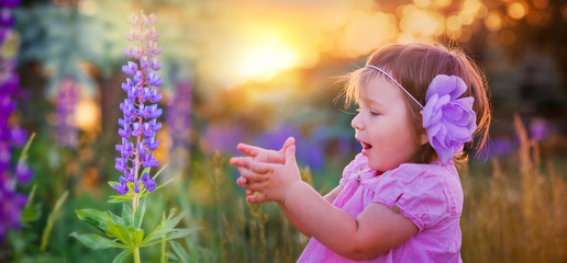 Portrait of little girl in a field of flowers at summer evening