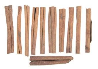 Cinnamon sticks lined up on white