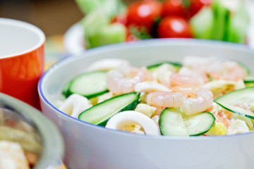Delicious salad with shrimps and cucumber on a festive table