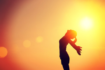 	cheering young woman hiker open arms at sunrise mountain peak 