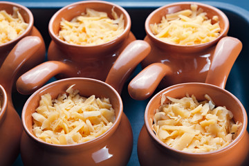 Roast with vegetables, meat and cheese in pottery.