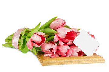 Pink tulips with satin ribbon on the wooden frame with postcard