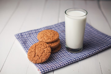 Oatmeal cookies and glass of milk on napkin on white table