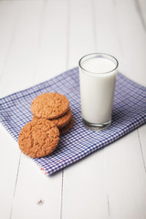 Oatmeal cookies and glass of milk on napkin on white table