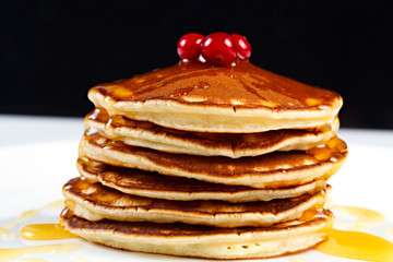 Pancakes with honey and cranberries on a plate.