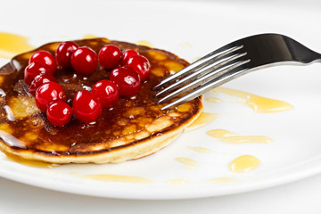 Fried pancakes with cranberry heart shaped with honey on a plate
