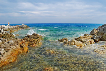 Fototapeta na wymiar Sunny coastal landscape with rocks, agitated sea and cloudy sky