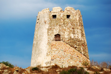 Naklejka premium Spanish ancient tower in the coast with vivid blue sky back