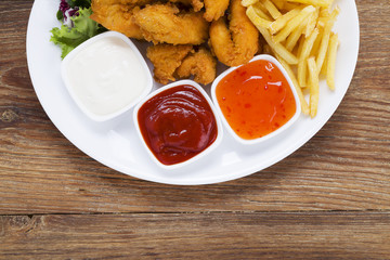 Nuggets and chips on a plate served with dip and salads