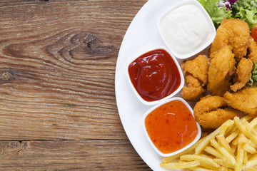 Nuggets and chips on a plate served with dip and salads