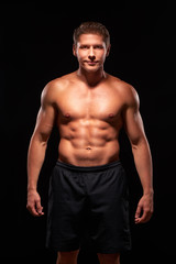Fototapeta na wymiar Portrait of a powerful smiling athletic man on black background