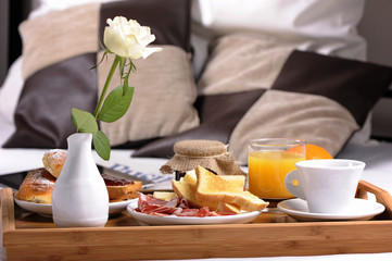 Tray with breakfast on a bed in a hotel room