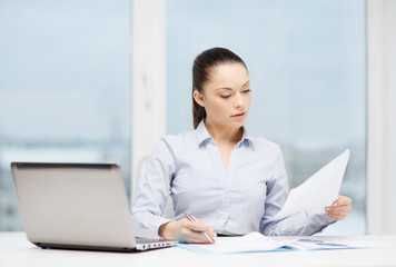 businesswoman with laptop and charts in office