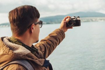 Obraz premium Young man takes photographs self-portrait on coast