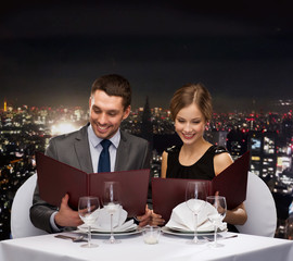 smiling couple with menus at restaurant