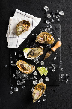 Fresh oysters on a black stone plate top view