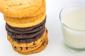variety of cookies stacked and glass of milk