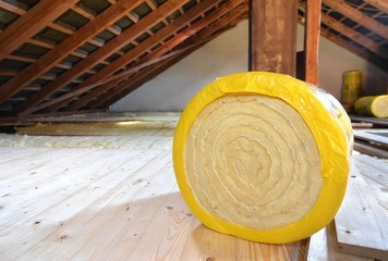 A roll of insulating glass wool on an attic floor - obrazy, fototapety, plakaty