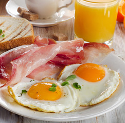 Two fried eggs, bacon,toasts, juice and coffee.
