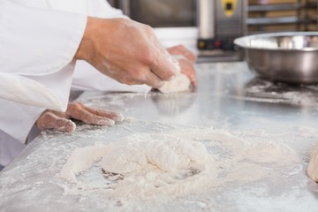 Close up of bakers kneading dough at counter