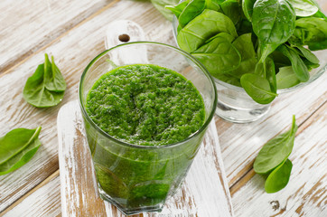 spinach smoothie in glass on  wooden background