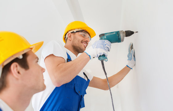 group of smiling builders with drill indoors