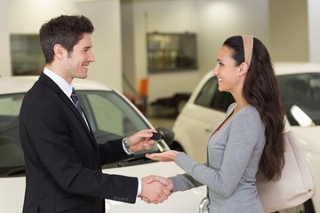 Businessman giving car key while shaking a customer hand