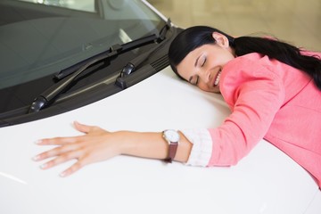 Smiling woman hugging a white car