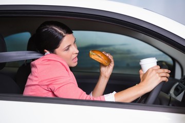 Woman drinking coffee and eating sandwich on phone
