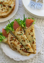 Thin rolled pancakes, crepes with salmon. Traditional Russian