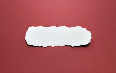 A piece of torn paper on a red background