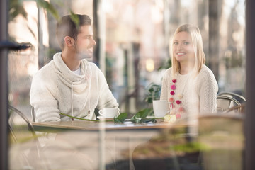 Two smiling young people sitting in a coffe shop