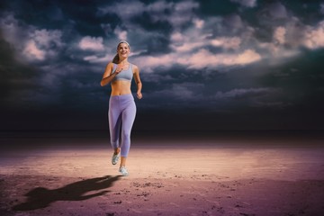 Composite image of sporty blonde jogging towards camera