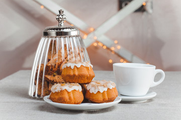 table with cup and three cupcake in glaze light background