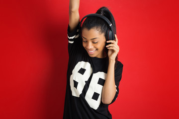 Beautiful brazilian teenager with headphones against red backgro
