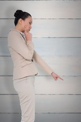 Composite image of thoughtful asian businesswoman pointing
